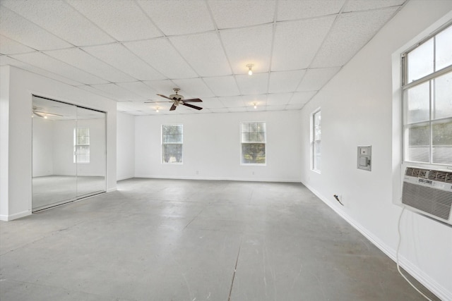 unfurnished room with plenty of natural light, a paneled ceiling, and baseboards