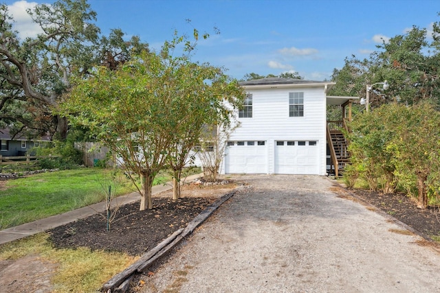 view of front of home featuring driveway, a front lawn, stairway, and an attached garage