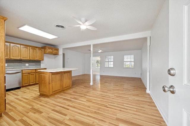 kitchen featuring a ceiling fan, dishwasher, a kitchen island, light countertops, and light wood-type flooring