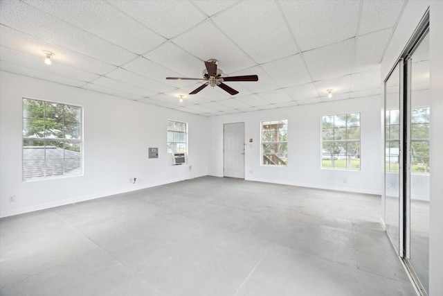 empty room featuring plenty of natural light, concrete flooring, and a drop ceiling