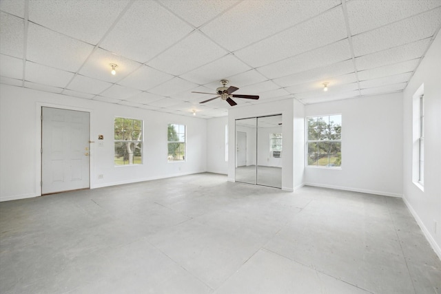 unfurnished room featuring a paneled ceiling, ceiling fan, concrete floors, and baseboards