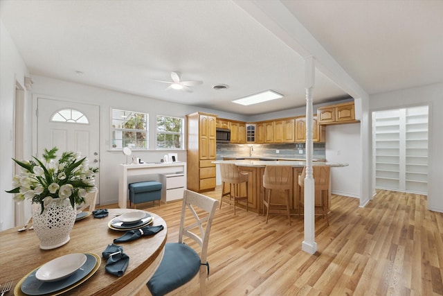 dining room with ceiling fan, light wood finished floors, and baseboards