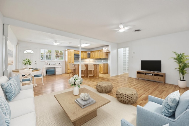 living area featuring light wood finished floors, ceiling fan, and visible vents