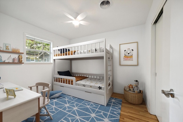 bedroom with ceiling fan, a closet, wood finished floors, and visible vents