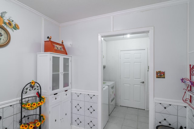 laundry area with cabinets, light tile patterned floors, tile walls, washing machine and clothes dryer, and ornamental molding