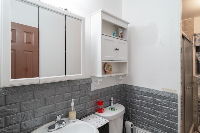 bathroom with sink, toilet, a shower with shower door, and backsplash