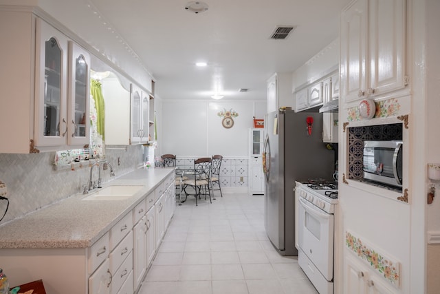 kitchen with range hood, gas range gas stove, sink, light tile patterned floors, and tasteful backsplash