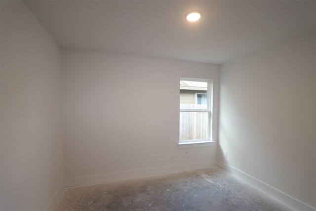 unfurnished room with unfinished concrete floors and baseboards