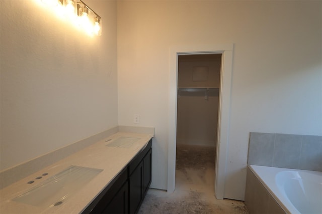 full bath featuring concrete flooring, a tub to relax in, a sink, double vanity, and a walk in closet