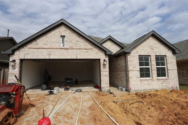 french provincial home featuring brick siding, a garage, and driveway