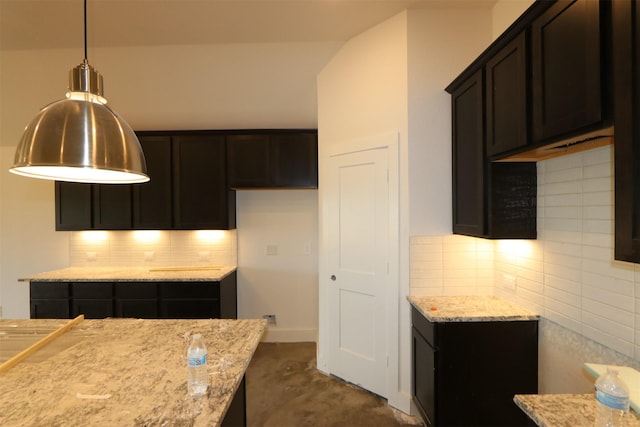 kitchen featuring light stone counters, baseboards, hanging light fixtures, dark brown cabinets, and tasteful backsplash