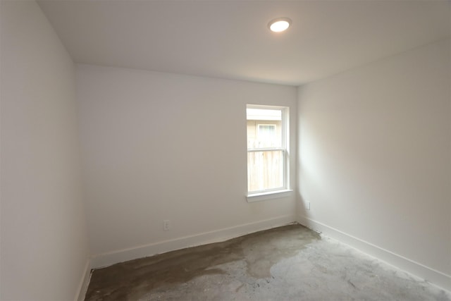 spare room featuring concrete flooring and baseboards