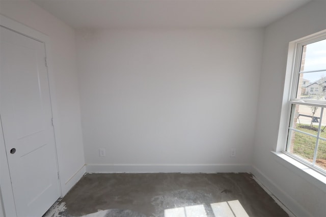 empty room with concrete flooring, baseboards, and a wealth of natural light