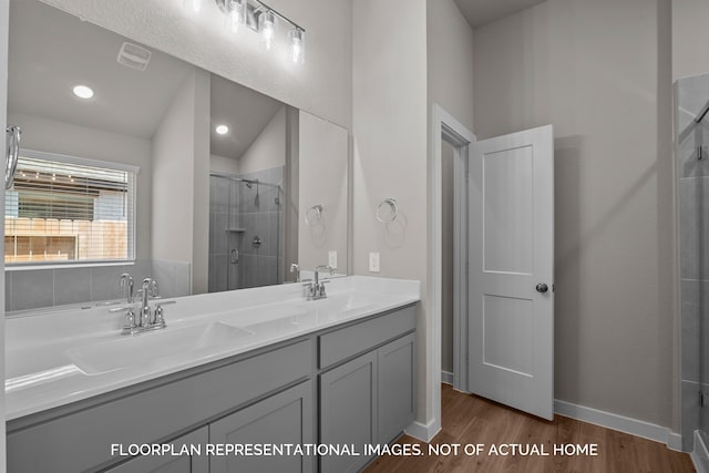 bathroom with vanity, wood-type flooring, vaulted ceiling, and a shower with door