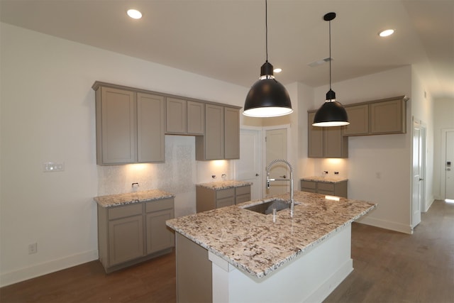 kitchen featuring a kitchen island with sink, sink, light stone countertops, and dark hardwood / wood-style floors