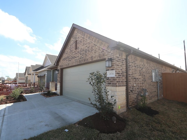 view of home's exterior featuring a garage, brick siding, and driveway