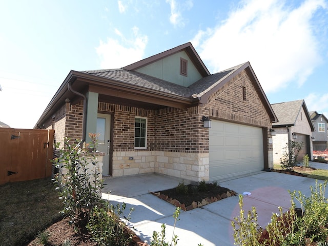 view of home's exterior featuring a shingled roof, concrete driveway, a garage, stone siding, and brick siding