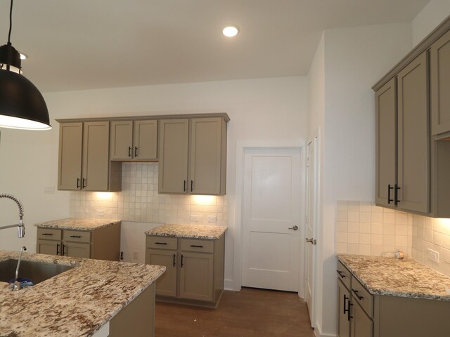 kitchen with light stone counters, gray cabinetry, and a sink