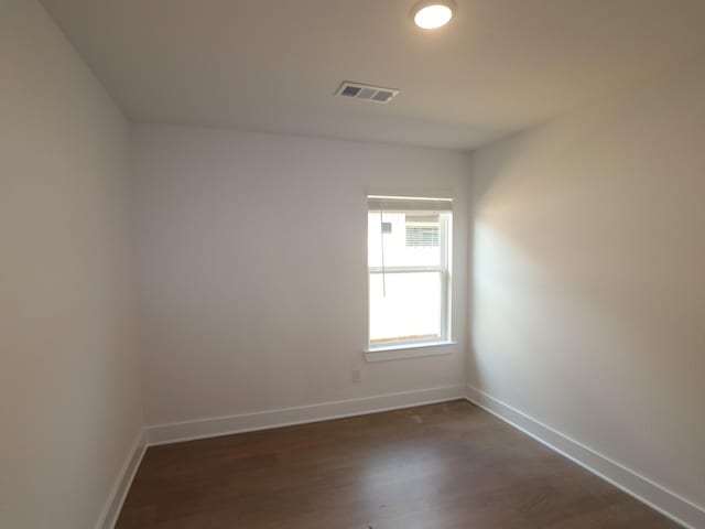 spare room with visible vents, baseboards, and dark wood-style flooring