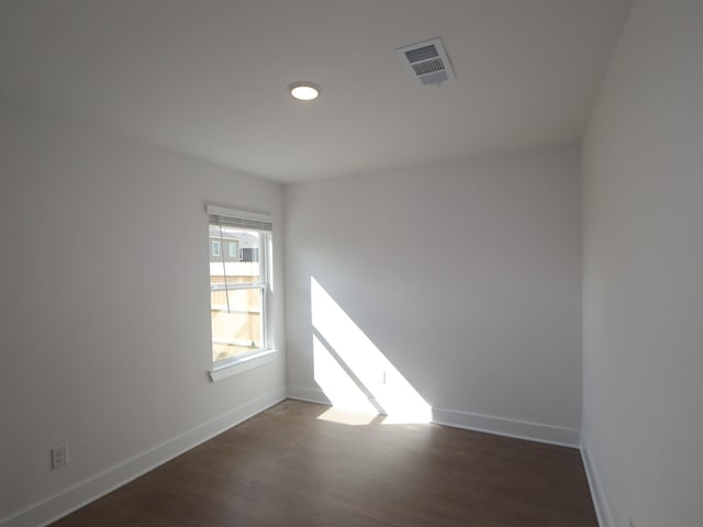 spare room featuring wood finished floors, visible vents, and baseboards