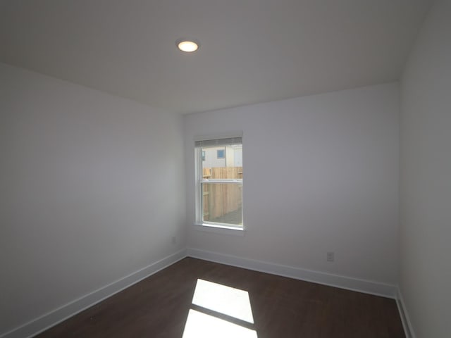 spare room with dark wood-type flooring and baseboards