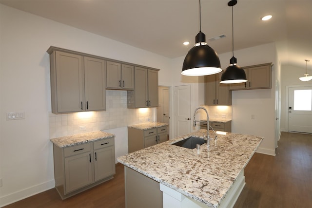 kitchen with a sink, light stone countertops, and gray cabinets