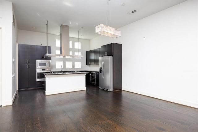 kitchen featuring island exhaust hood, appliances with stainless steel finishes, decorative light fixtures, and dark hardwood / wood-style floors