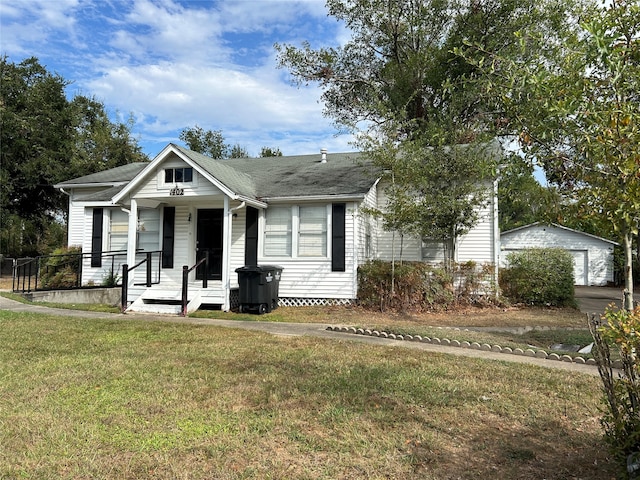 view of front of house with covered porch, a front yard, and an outdoor structure