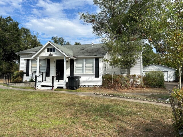 view of front of home with covered porch, an outbuilding, and a front lawn