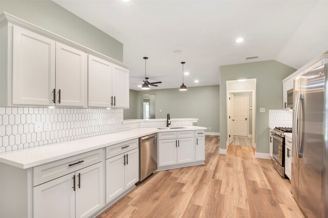 kitchen featuring kitchen peninsula, white cabinetry, light hardwood / wood-style flooring, sink, and stainless steel appliances