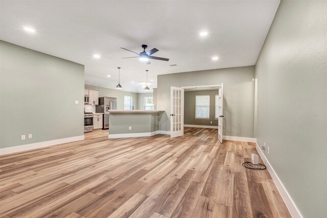 unfurnished living room featuring french doors, ceiling fan, and light hardwood / wood-style flooring