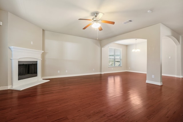 unfurnished living room featuring dark wood-type flooring and ceiling fan with notable chandelier