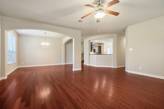 unfurnished living room featuring dark wood-type flooring and ceiling fan with notable chandelier