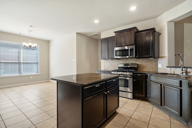 kitchen featuring a kitchen island, backsplash, stainless steel appliances, pendant lighting, and a chandelier