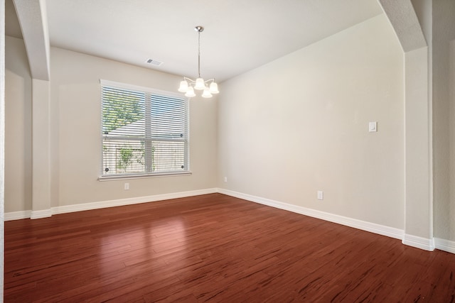 unfurnished room with dark wood-type flooring and a chandelier