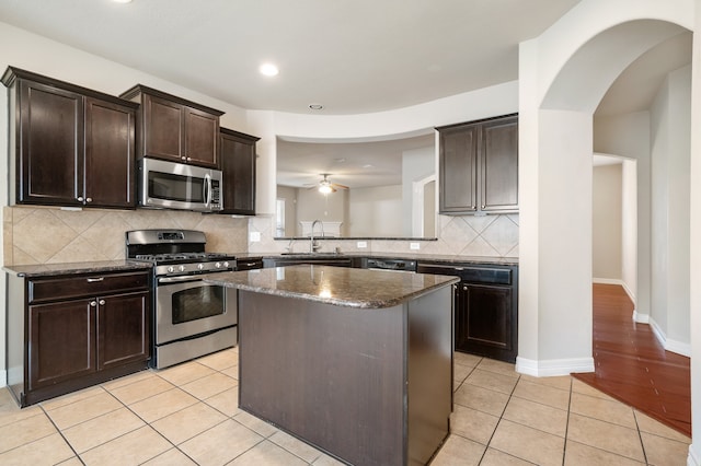 kitchen featuring light tile patterned floors, stainless steel appliances, sink, dark brown cabinetry, and a center island