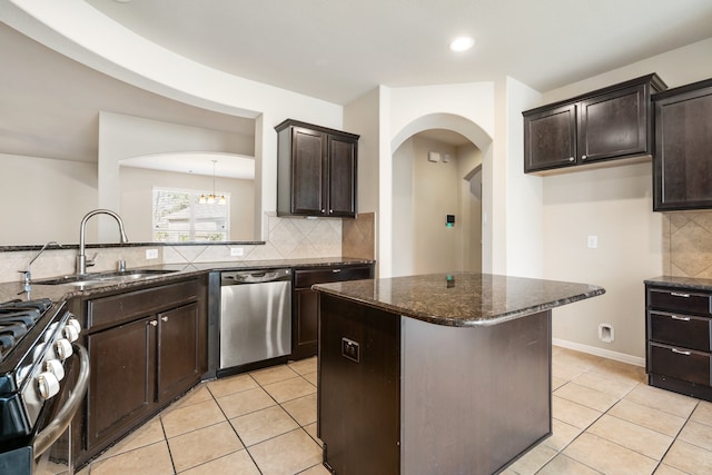 kitchen featuring dark brown cabinets, dark stone counters, sink, light tile patterned flooring, and appliances with stainless steel finishes