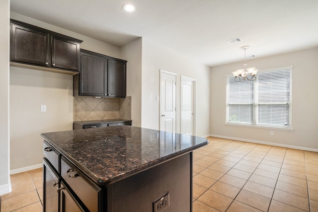 kitchen with a kitchen island, decorative backsplash, dark stone counters, a notable chandelier, and decorative light fixtures