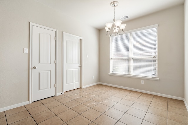 unfurnished room with light tile patterned flooring, a notable chandelier, and plenty of natural light