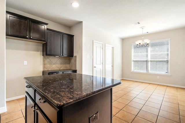 kitchen with a notable chandelier, light tile patterned floors, tasteful backsplash, dark stone countertops, and baseboards