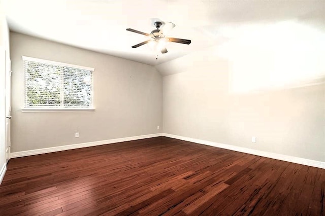 spare room with vaulted ceiling, baseboards, dark wood finished floors, and a ceiling fan