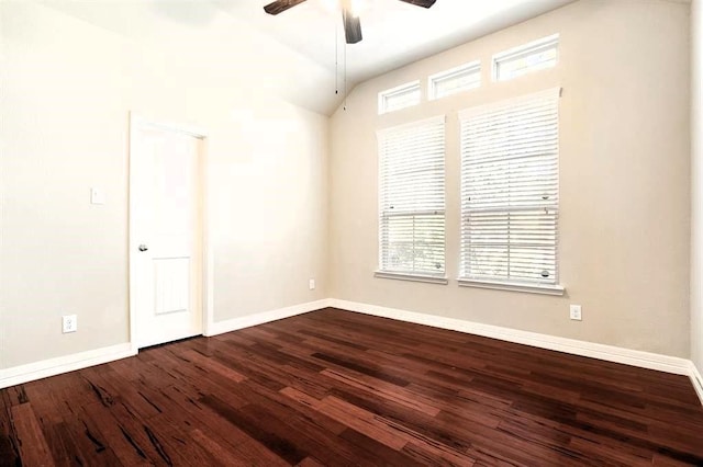 empty room with a healthy amount of sunlight, dark wood-style floors, baseboards, and lofted ceiling