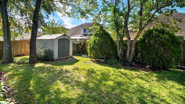 view of yard featuring a storage shed, a fenced backyard, and an outbuilding