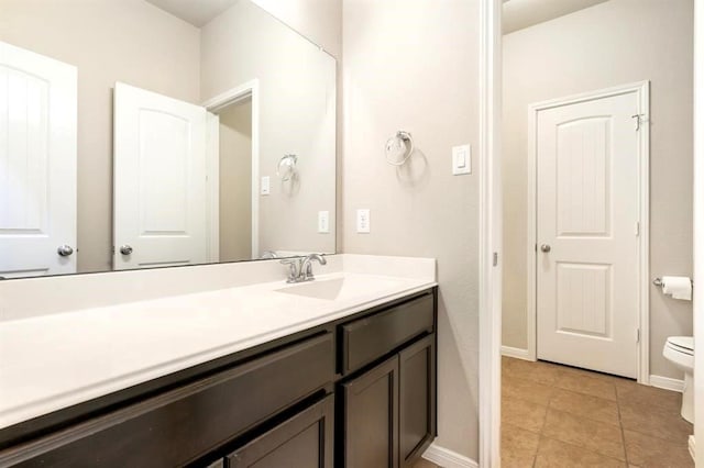 bathroom with baseboards, vanity, toilet, and tile patterned floors