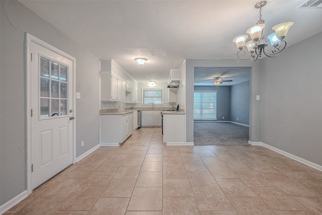 kitchen featuring hanging light fixtures, sink, light tile patterned floors, white cabinets, and ceiling fan with notable chandelier