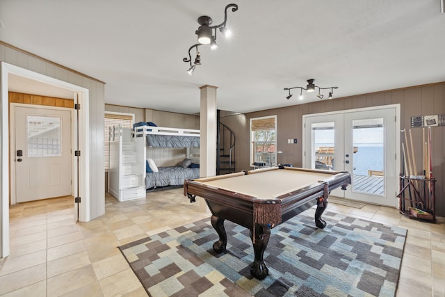 rec room featuring french doors, light tile patterned floors, and wooden walls