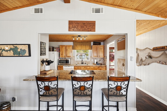 kitchen with lofted ceiling, wood ceiling, wood walls, white fridge, and sink