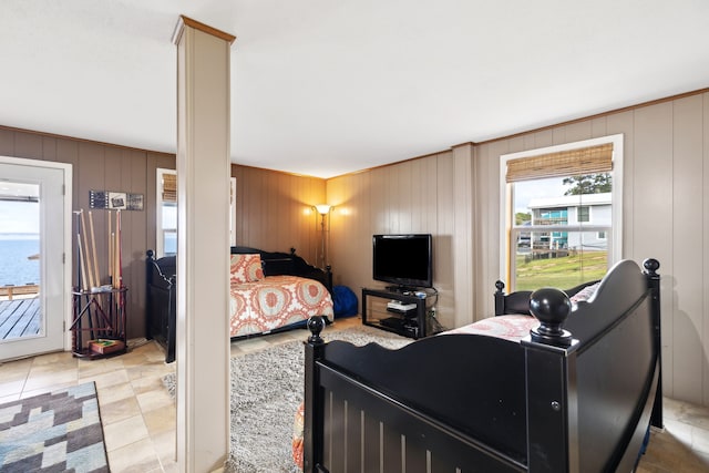 tiled bedroom with access to exterior, wooden walls, and a water view