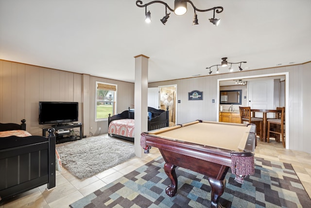 recreation room with wood walls, sink, ornate columns, and light tile patterned floors