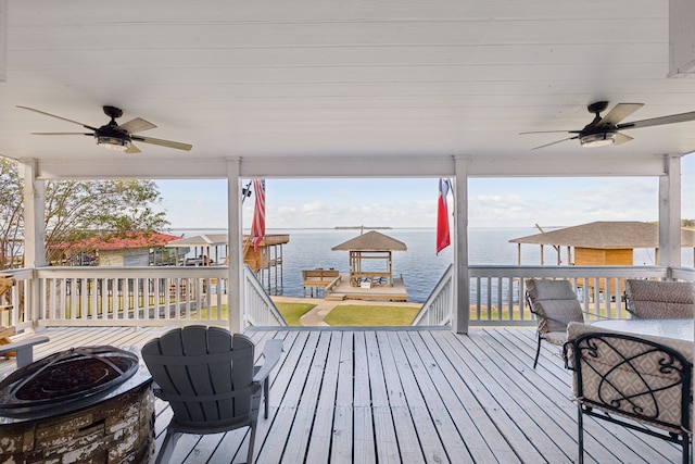 deck with an outdoor fire pit, a water view, and ceiling fan